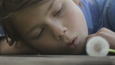 Bir çiçek karahindiba ile bir çocuk portresi. Yüz yakın çekim çocuk karahindiba ile. Duygusal bir Avrupa genç bir çiçek karahindiba ile portresi.