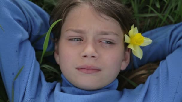 Retrato de un niño en primavera con una flor de narciso amarillo. Niño oculto oliendo narciso de flores. La cara del chico adolescente con una flor en la mano . — Vídeo de stock