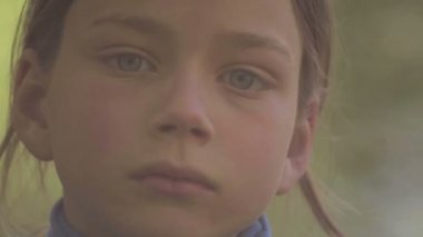 Üzgün çocuk kameraya benziyor. Kameraya bakarak üzgün çocuk portresi. Çocuk arıyorsunuz kamera sonra gülümsüyor pişmanlık ile. Yüzünü kapat. 