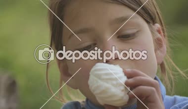 Çocuk açık havada şekerleme yiyor. Marshmallow elinde beyaz tenli bir çocukla portresi. Çocuk bir tatlı tatlı yiyor.