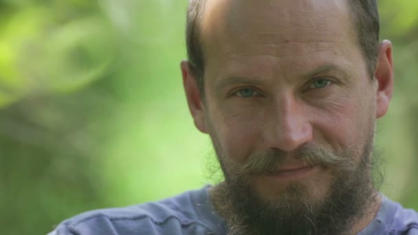 Retrato de un hombre barbudo con flor de peonía en las manos. El hombre barbudo inhala la fragancia de una flor. El hombre cara de cerca con una flor . — Vídeos de Stock