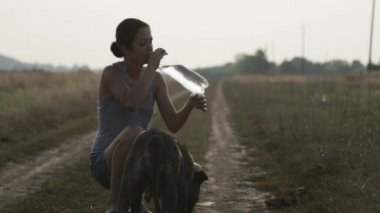Bir şişe genç kadınla köpek sulanır. Korkunç içme suyu bir şişe. Kızla köpek şarkı eller. 