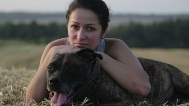 Junge Frau mit Hund in der Krippe. Porträt eines Mädchens auf einem Feld mit einem Terrier. Menschen, Natur, Haustiere, — Stockvideo
