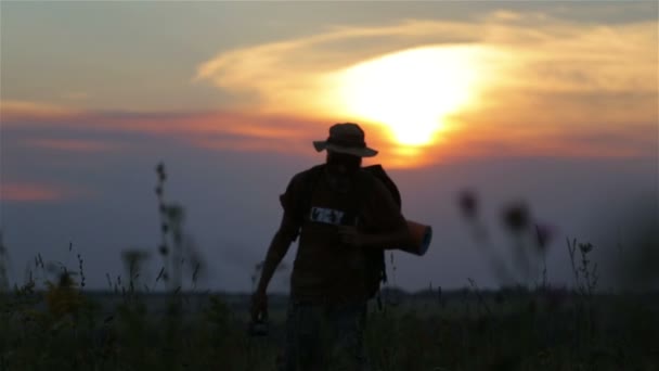 Турист з рюкзаком і фотоапаратом на заході сонця в полі. Бородатий чоловік мандрівник робить селфі на заході сонця . — стокове відео