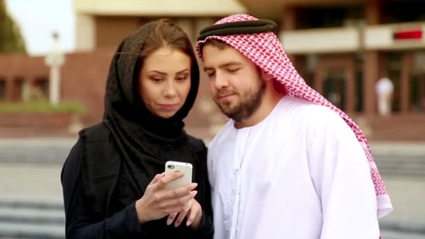 Junges Paar in arabischer Kleidung vor dem Hintergrund der Stadt. Porträt eines schönen jungen Paares im arabischen Nationalkleid. Araberin telefoniert. — Stockvideo