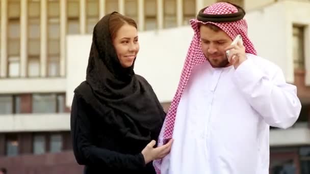 都市の背景にアラビアの服の若いカップル。アラブ国家で美しい若いカップルの肖像画をドレスアップします。電話で話すのアラブ人. — ストック動画