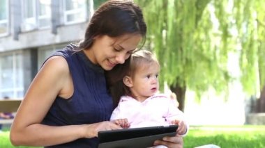 Anne tablet.young anne bebek parkta oynarken laptop ile oynamak için bir çocuk biraz girl.mom öğretir öğretir.