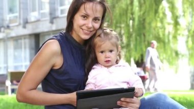 Anne tablet.young anne bebek parkta oynarken laptop ile oynamak için bir çocuk biraz girl.mom öğretir öğretir.