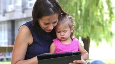 Anne tablet.young anne bebek parkta oynarken laptop ile oynamak için bir çocuk biraz girl.mom öğretir öğretir.