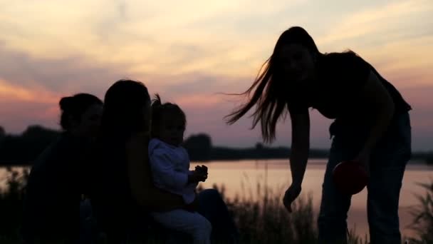 Girlfriend with baby on sunset.Silhouette of three girls with a child.Three mothers with baby on nature.Young mother with baby at the lake at sunset. — Stock video