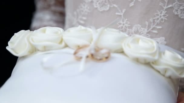 Meisje bedrijf trouwringen. Trouwringen op een wit kussen. Twee Gouden trouwringen op een kussen. — Stockvideo