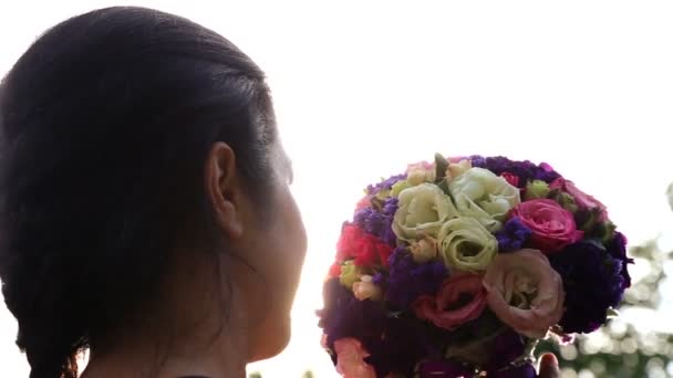 Brautstrauß in der Sonne. Brautstrauß in den Händen der Braut bei Sonnenuntergang. Mädchen mit Blumenstrauß im Sonnenlicht. — Stockvideo