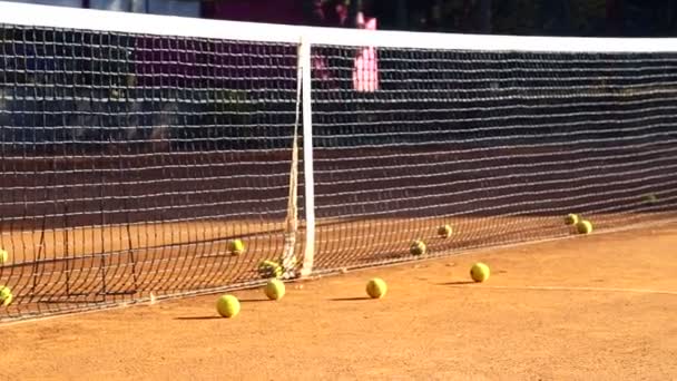 Pista de tenis antes del juego.Bolas en la cancha de tenis. Bolas rodar hacia abajo para cubrir una cancha de tenis . — Vídeo de stock