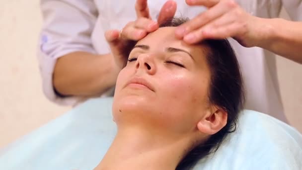 Masaje facial hermosa chica.Retrato de una chica en un salón de masaje.esteticista haciendo masaje de rostros femeninos.Masaje cara chica primer plano . — Vídeos de Stock