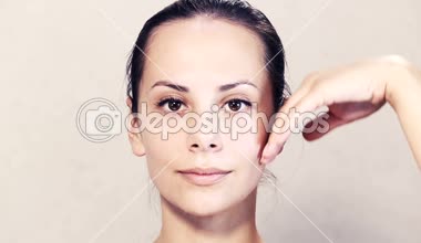 Kameraya poz güzel bir genç kız portresi. Güzel bir genç kadının yüz masaj yapıyor. Yüz Cilt Bakımı yüz için egzersizler. Bir kız closeup yüz portresi.