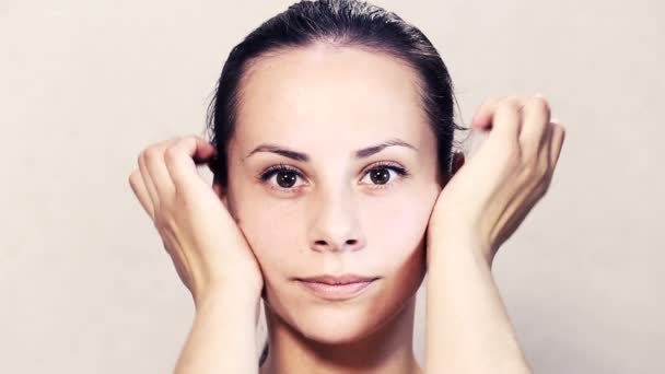 Portrait of a beautiful young girl posing at the camera.Face of a beautiful young woman is doing massage.Exercises for the face, skin care face.Face portrait of a girl closeup. — Stock Video