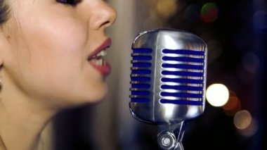 Genç güzel kız şarkı söylüyor. Genç şarkıcı bir mikrofona şarkı. Portre ve şarkıcı kapatın. Club retro müzik konser.