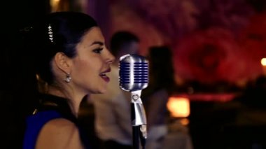 Genç güzel kız şarkı söylüyor. Genç şarkıcı bir mikrofona şarkı. Portre ve şarkıcı kapatın. Club retro müzik konser.