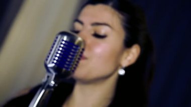 Genç güzel kız şarkı söylüyor. Genç şarkıcı bir mikrofona şarkı. Portre ve şarkıcı kapatın. Club retro müzik konser.