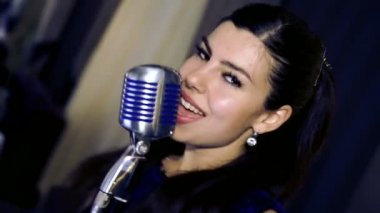 Genç güzel kız şarkı söylüyor. Genç şarkıcı bir mikrofona şarkı. Portre ve şarkıcı kapatın. Club retro müzik konser.