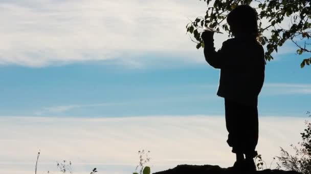 Silhuetten av en pojke som leker med ett pappersflygplan. Lonely boy spelar utomhus. Barnet börjar plan på himmel bakgrund. — Stockvideo