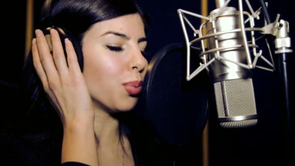 Όμορφη κοπέλα που τραγουδάει. Νεαρός τραγουδιστής τραγουδά σε ένα μικρόφωνο. Πορτρέτο κοντινό πλάνο του τραγουδιστή. Στούντιο ηχογράφησης. Καταγραφή σε οι τραγουδιστές στούντιο. — Αρχείο Βίντεο