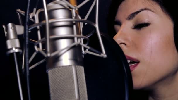 Young beautiful girl sings.Young singer singing into a microphone.Portrait close up of the singer.Recording studio.Recording in the studio singers. — Stock Video