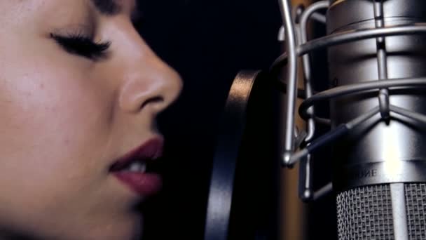 Joven hermosa chica canta. Joven cantante cantando en un micrófono. Retrato de cerca del cantante. Estudio de grabación. Grabación en los cantantes de estudio. . — Vídeos de Stock