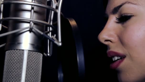 Young beautiful girl sings.Young singer singing into a microphone.Portrait close up of the singer.Recording studio.Recording in the studio singers. — Stock Video