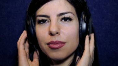 Kulaklık ile müzik keyfi bir genç kız portresi. Genç kız yakın çekim kulaklık. Yüzü güzel bir genç kız müzik dinliyor. Kız kameraya bakarak duygusal Kulaklığımda.