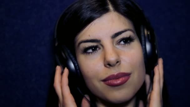 Retrato de una joven disfrutando de la música con auriculares. Muchacha joven de cerca en los auriculares. Rostro de una hermosa joven escucha música. Muchacha en auriculares emocional mirando a la cámara . — Vídeos de Stock