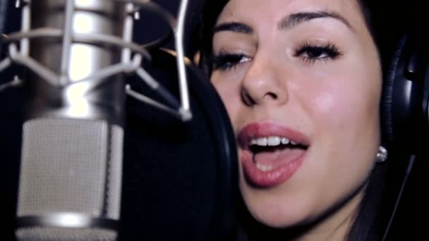 Joven hermosa chica canta. Joven cantante cantando en un micrófono. Retrato de cerca del cantante. Estudio de grabación. Grabación en los cantantes de estudio. . — Vídeos de Stock