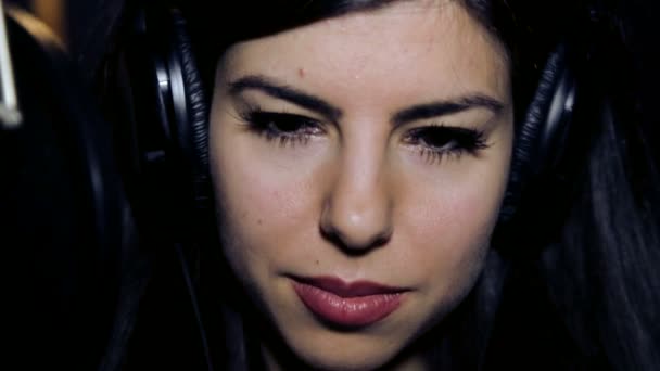 Portrait of a young girl enjoying music with headphones.Young girl close-up in the headphones.Face of a beautiful young girl listens to music.Girl in headphones emotional looking at the camera. — Stock Video