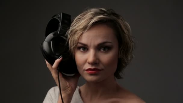 Porträtt av vacker flicka i hörlurar. Kvinnan blond närbild lyssnar på musik. Ung vacker tjej njuter musik. — Stockvideo