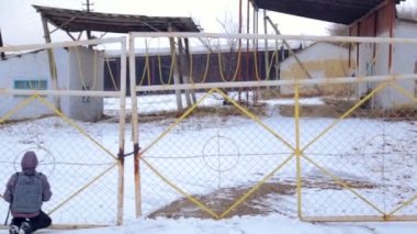 Kışın terk edilmiş bir çiftlik, beyaz çocuk. Eski çiftlikte yürüyen bir genç çocuktur. Bir çocuk, yakın çekim barlar çitin üzerinden portresi.