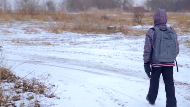 Kaukasiska pojke tonåring resa i vinter. Barnet går på en Vinterväg genom fälten. Målmedveten tonåring övervinner den hårda vägen. — Stockvideo