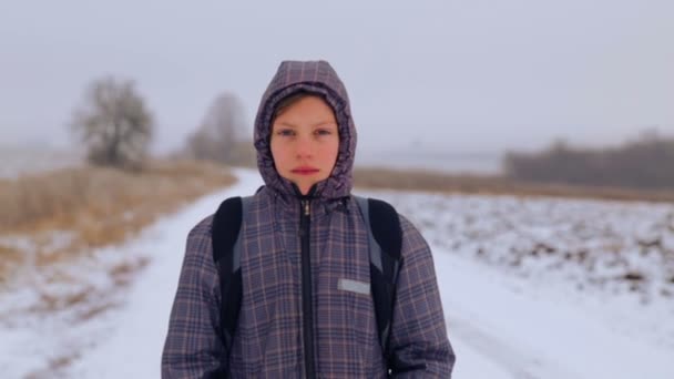 Beyaz çocuk genç Kışın seyahat. Çocuk alanlar arasında bir kış yolda gidiyor. Maksatlı genç zor yoldan üstesinden gelir.. — Stok video