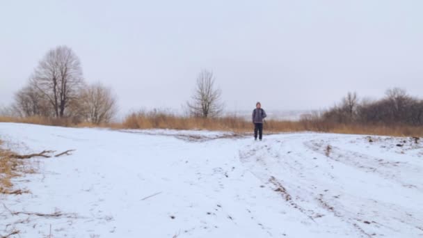 Kavkazská chlapec teenager cestování v zimě. Dítě jde na Zimní silnici přes pole. Cílevědomé teenager překonává po zlém. — Stock video