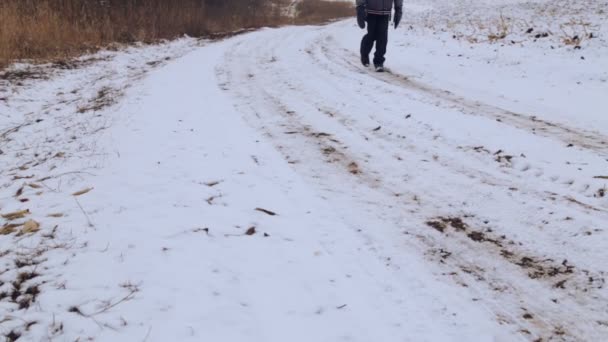 在冬季旅行的白人男孩少年。孩子在冬季道路穿过农田去。有目的的少年克服了硬的方式. — 图库视频影像