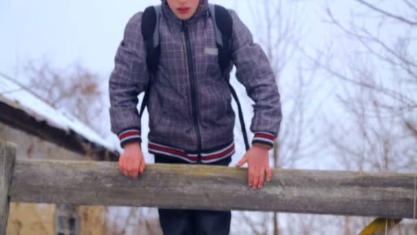 Niño caucásico cerca del edificio de la escuela del pueblo. Un niño camina y sube cerca de la vieja casa. País chico adolescente . — Vídeos de Stock