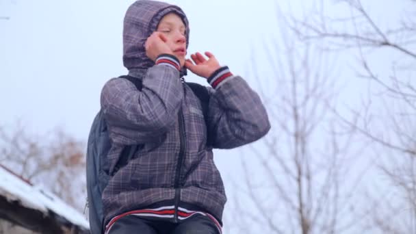 Kaukasiska pojke nära byggnaden av byns skola. Ett barn går och klättrar nära det gamla huset. Country boy tonåring. — Stockvideo