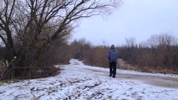 Kavkazská chlapec chodí do vesnické školy. Dítě je v pubertě, jde na Zimní silnici. Teenager s batohem chodí na Zimní silnici v obci. Chlapce, příroda, zimní cesta. — Stock video