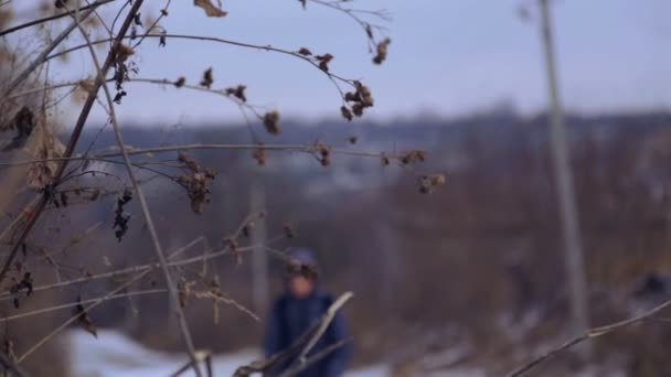 El chico caucásico va a la escuela del pueblo. El niño es un adolescente, va en camino de invierno. Un adolescente con una mochila va en camino de invierno en el pueblo. Niño, naturaleza, invierno, camino . — Vídeos de Stock