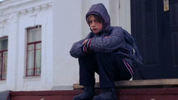 Niño caucásico cerca del edificio de la escuela del pueblo. Un niño camina y sube cerca de la vieja casa. País chico adolescente . — Vídeos de Stock