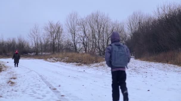 Kavkazská chlapec chodí do vesnické školy. Dítě je v pubertě, jde na Zimní silnici. Teenager s batohem chodí na Zimní silnici v obci. Chlapce, příroda, zimní cesta. — Stock video