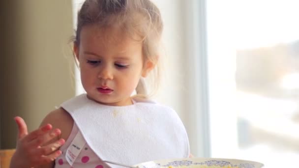 Kaukasische meisje eet onafhankelijk. Klein kind eet smakelijk. Portret van een kind-close-up die het voedsel eet. — Stockvideo