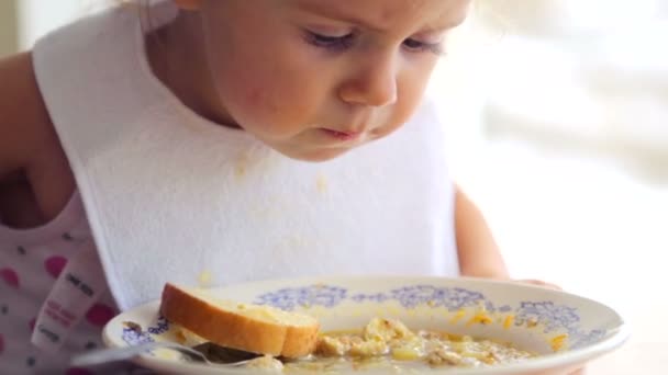 La niña caucásica come independientemente. El niño pequeño come apetitoso. Retrato de un niño de cerca que come la comida . — Vídeo de stock