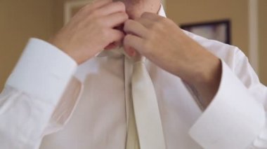 Genç bir adam bir kravat takıyor ve düğmeleri ile takılır. Beyaz adam kılığında. Erkeklerin günlük sabah alışkanlık. Festival kıyafetleri erkek.