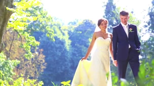 Sposi caucasici il giorno del matrimonio. Appena sposati, camminando sulla natura del giorno del matrimonio. Amanti, giovani sposi. Una giovane coppia che si diverte. Vacanza, matrimonio, felicità . — Video Stock