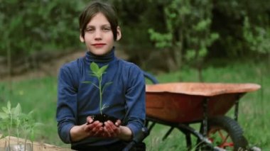 Beyaz çocuk bahçesinde bir yatakta. Çocuk bahar dikim yapmaktadır. Çocuk genç doğa yatağın yanında. Çocuk onun hands.Organic tarım bir fide ile.
